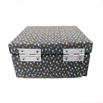 A rectangular dice storage box with a textured fabric cover featuring a multicolor dotted pattern on a dark gray background, secured with two silver metal latches on the back, set against a plain white background.