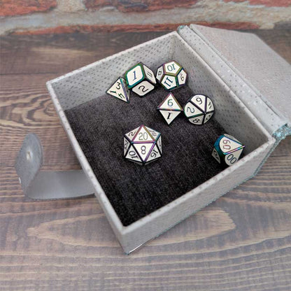 A 7-piece polyhedral gaming dice set displayed inside an open gray textured dice storage box with a dark plush lining, set on a wooden tabletop.