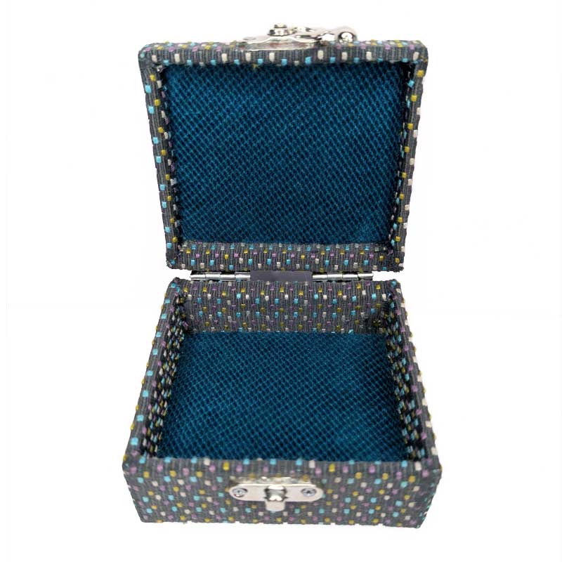 An open square dice box with a dark blue velvet-lined interior and a patterned exterior featuring small multicolored dots on a dark charcoal base, with silver-tone metal clasp hardware.