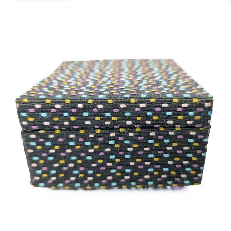 A square woven fabric box with a lid, featuring a gray base covered in a dense pattern of small multicolored dots in yellow, blue, purple, and white.